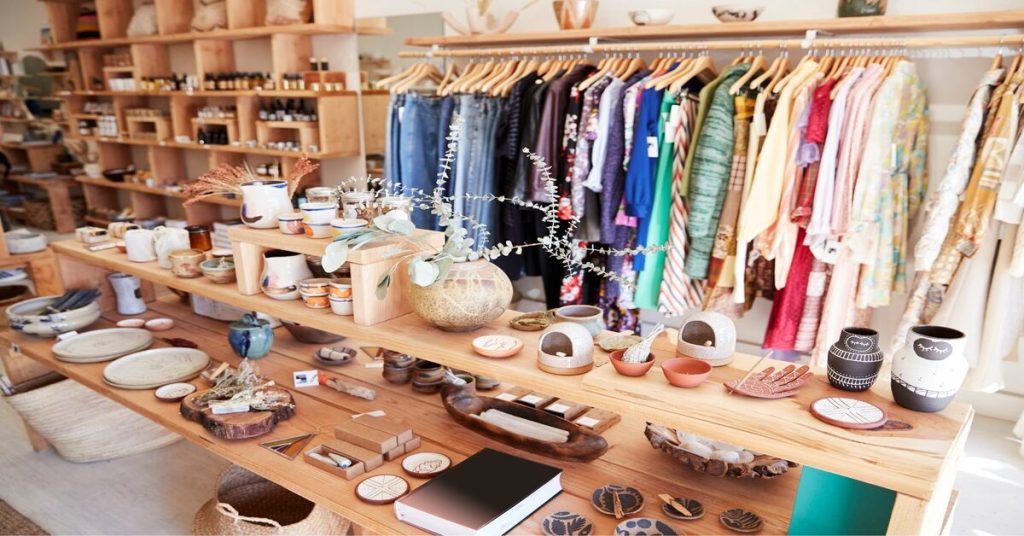 An interior view of a boutique store showcasing an assortment of pottery, clothes, and artisanal items, indicative of shopping and retail in the context of unique, possibly handmade goods.